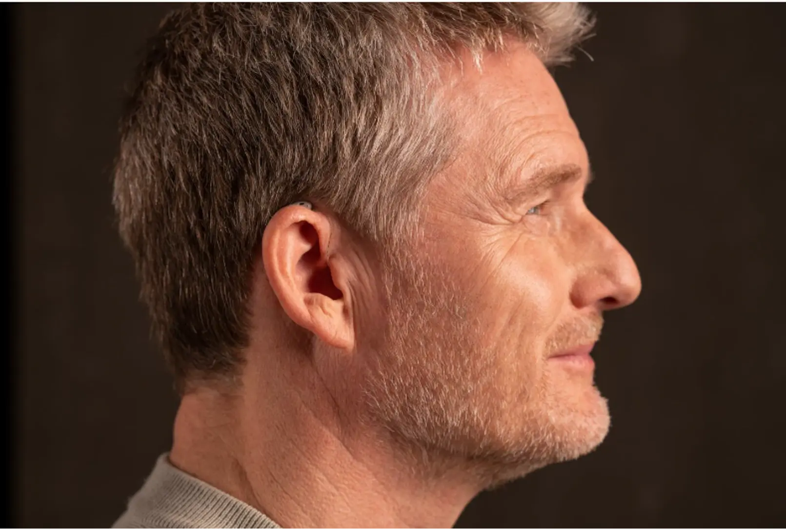 Idoso conversando sem zumbido no ouvido usando aparelho auditivo discreto